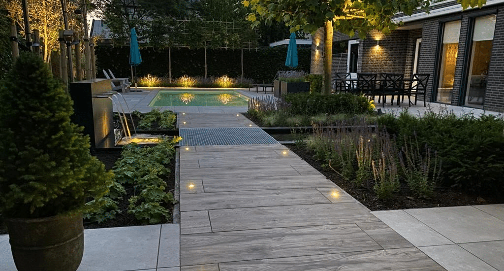 Sfeervolle tuin met keramische tegels, beplanting, spiegelvijver en verlichting